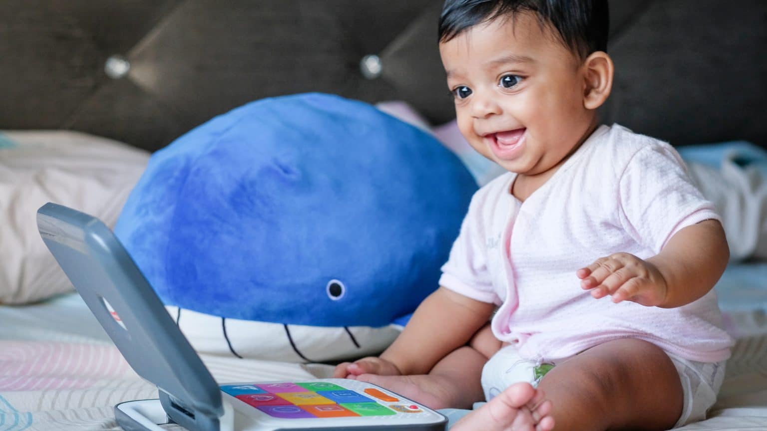 baby boy sitting up playing with a toy laptop