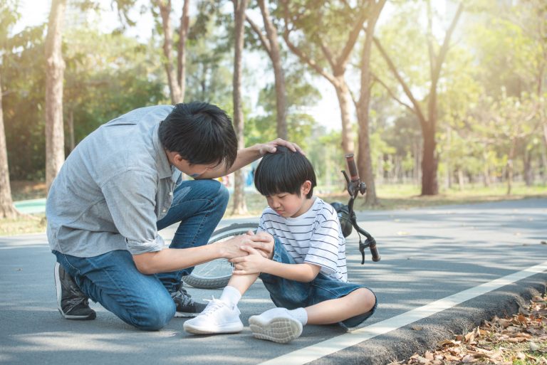 dad helping his son who fell off his bike