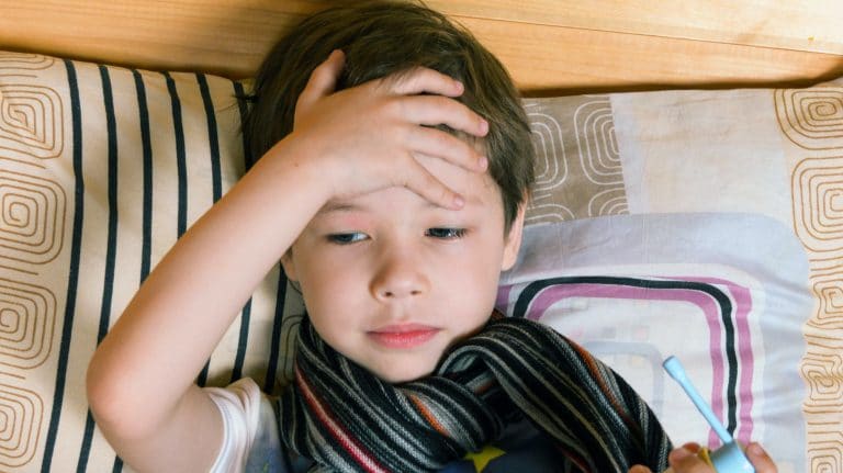 boy holding his head as if he isn't feeling well