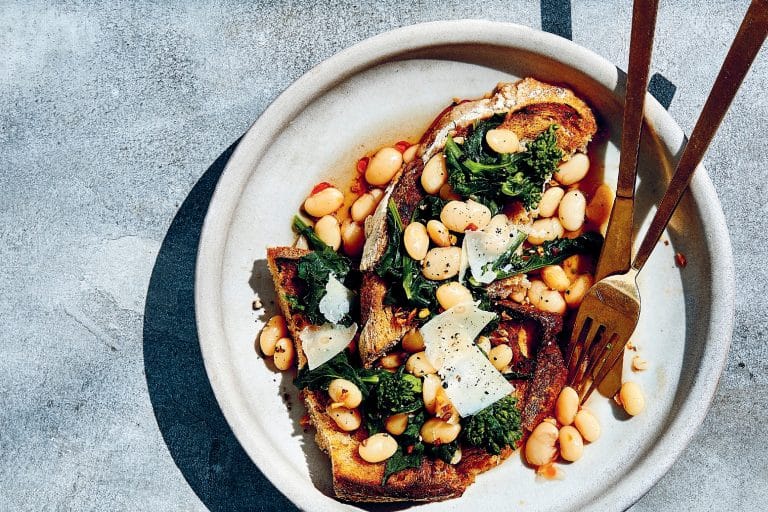 marinated beans over toast on a plate with a knife and fork