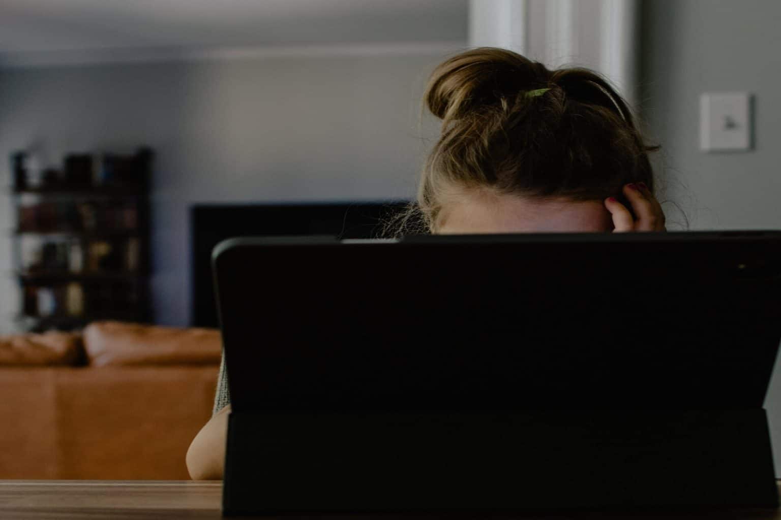 Woman with ponytail obscured by computer screen