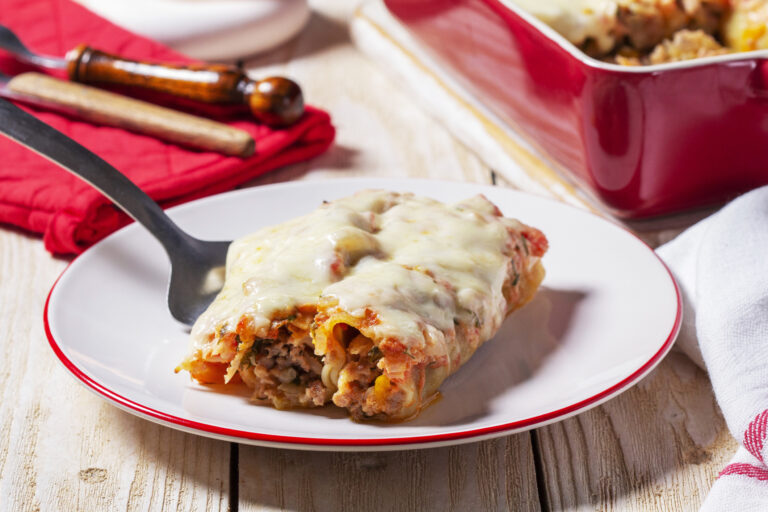Lasagna roll-ups on a white plate with a red napkin in the background