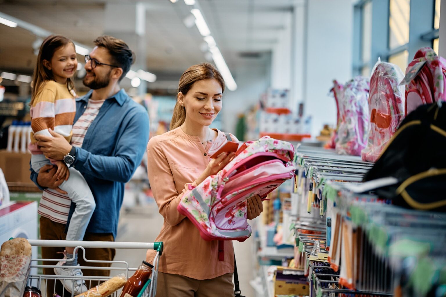 money saving tips on back to school shopping with a mom looking at backpacks in a store