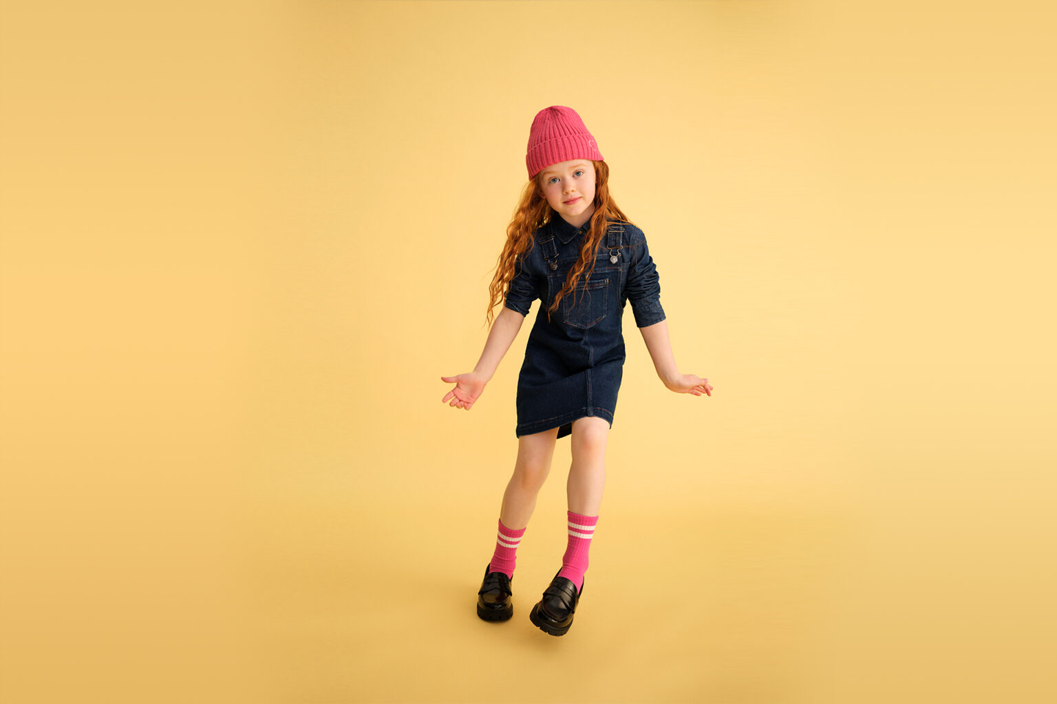 a girl wearing a pink hat and blue dress