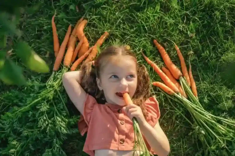 a girl lying on the grass eating a carrot