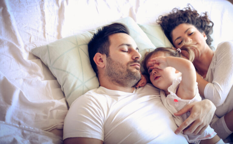 a man and woman lying in bed with a baby