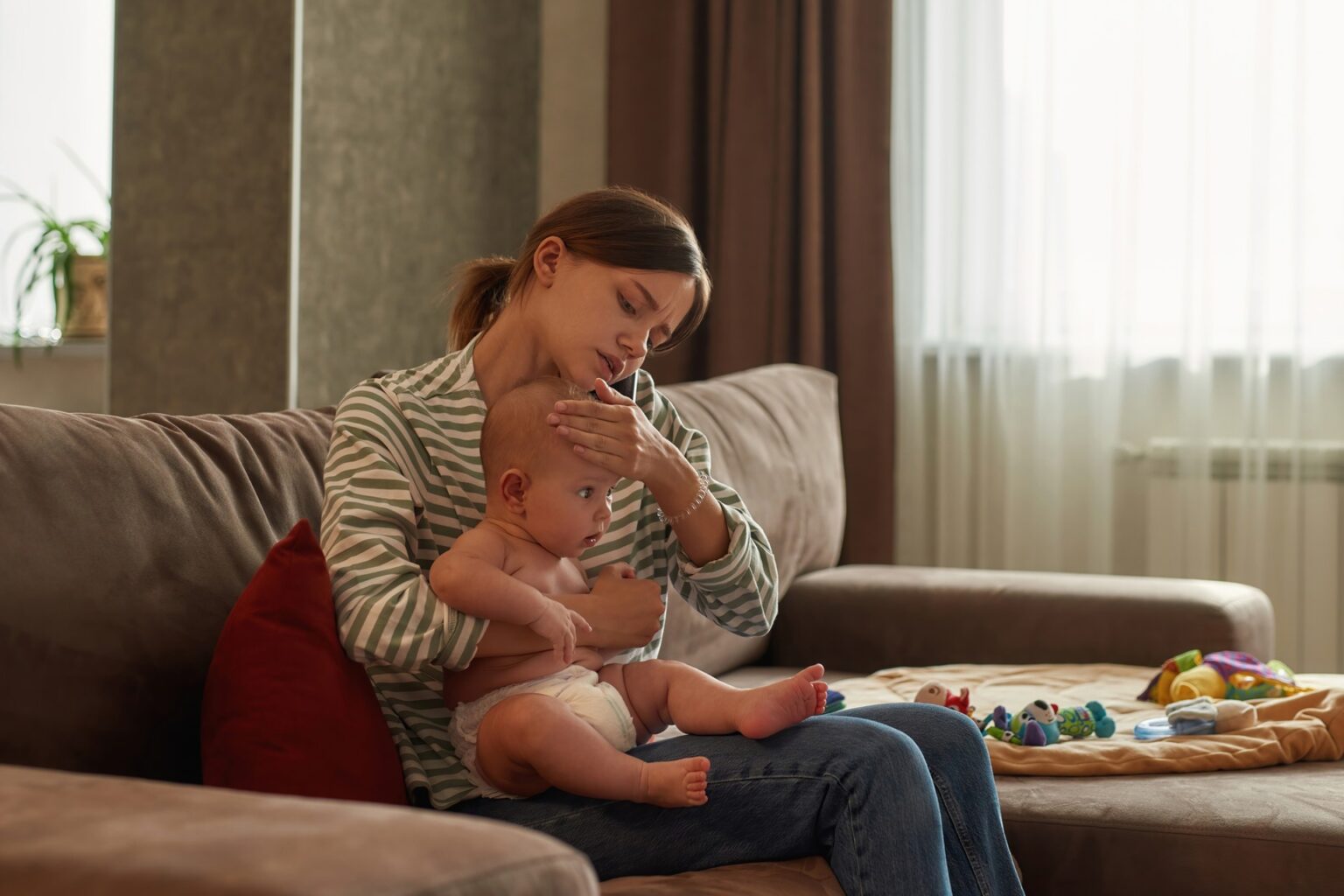 mother holds her toddler while on the phone wondering how to find a family doctor in canada