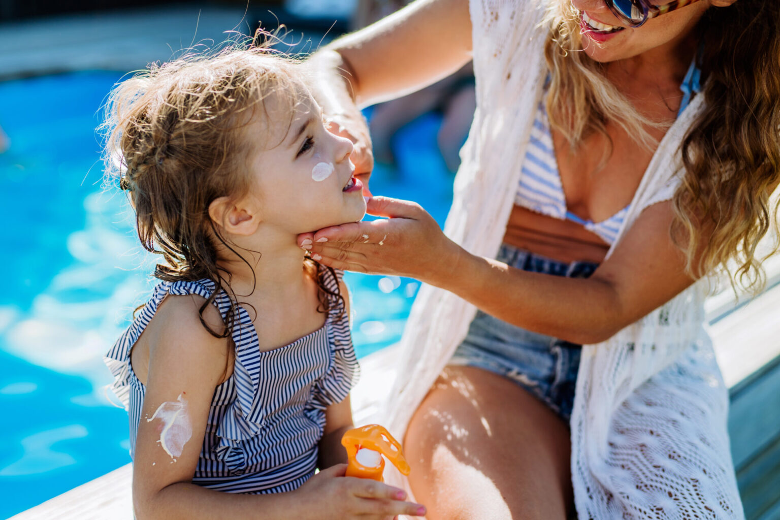 Mom putting sunscreen on daughter, for common childhood skincare questions answered