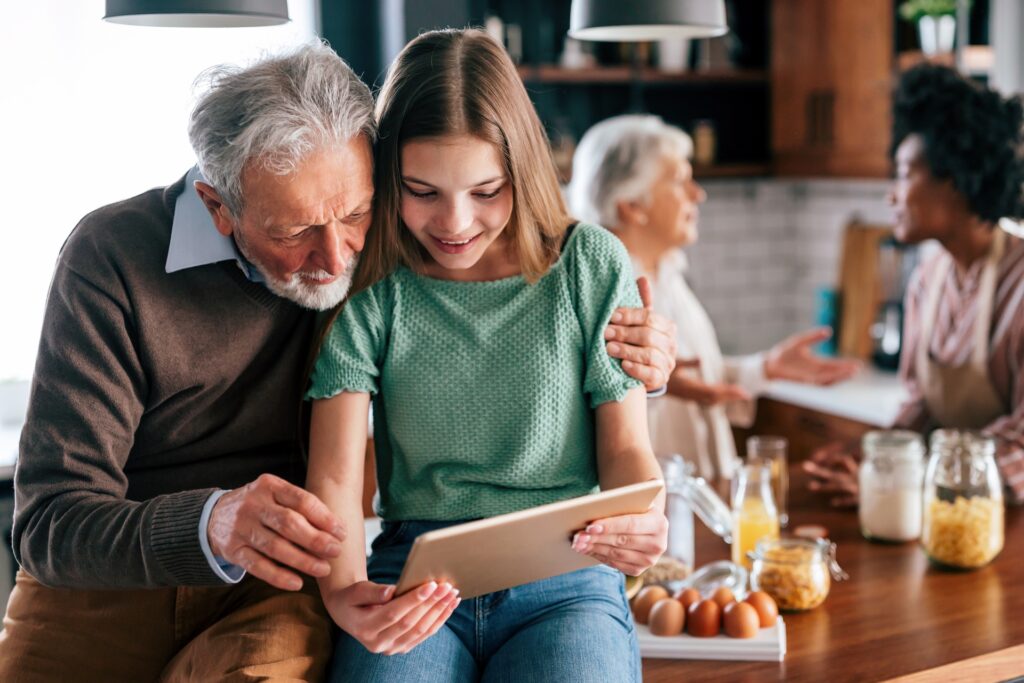 A grandparent and grandchild look at a tablet together