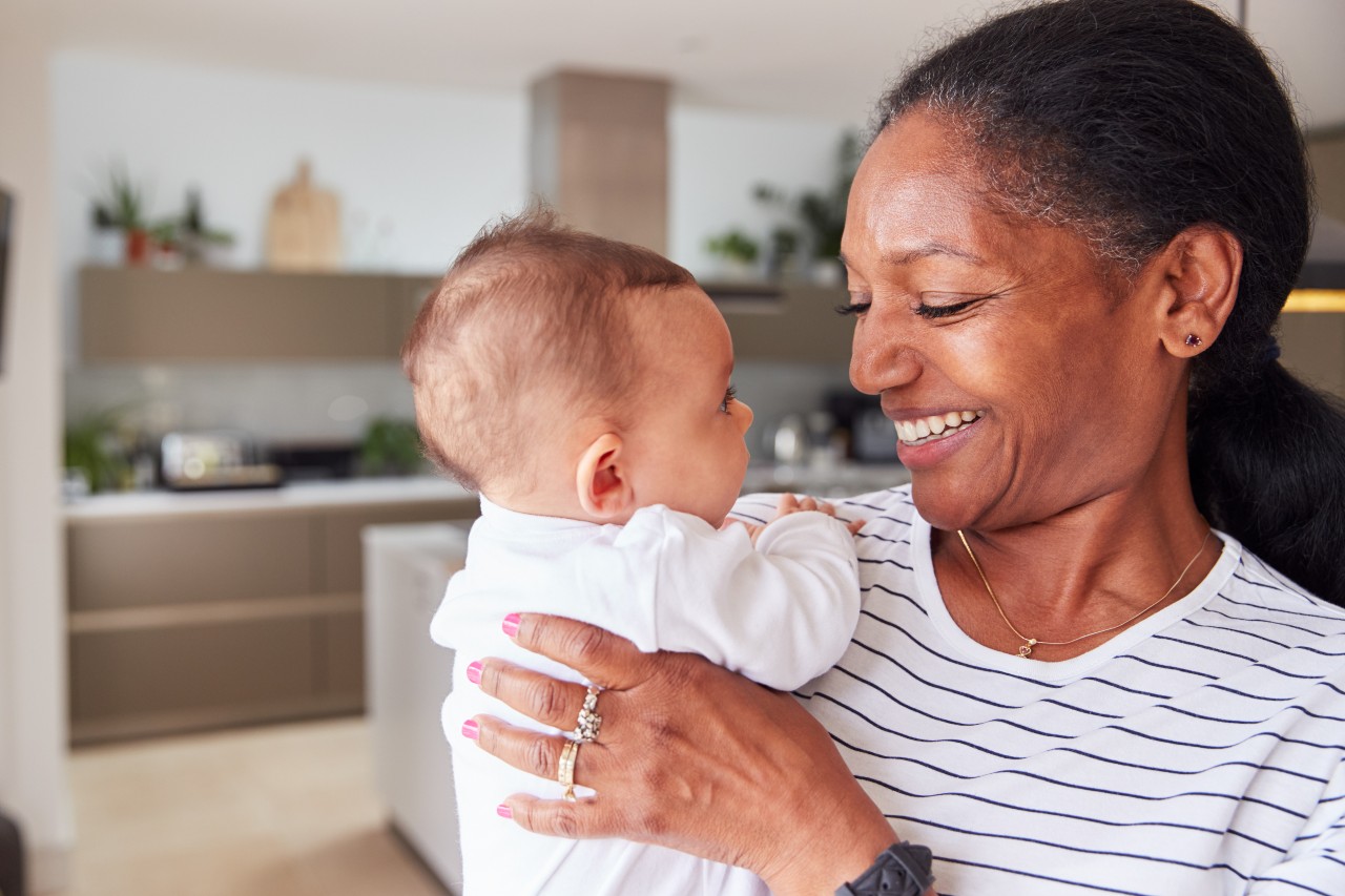 A grandmother holds her baby, looking down at the baby and appearing happy