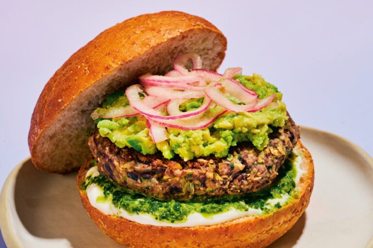 A cumin lime black bean burger sits on a plate with all the fixings