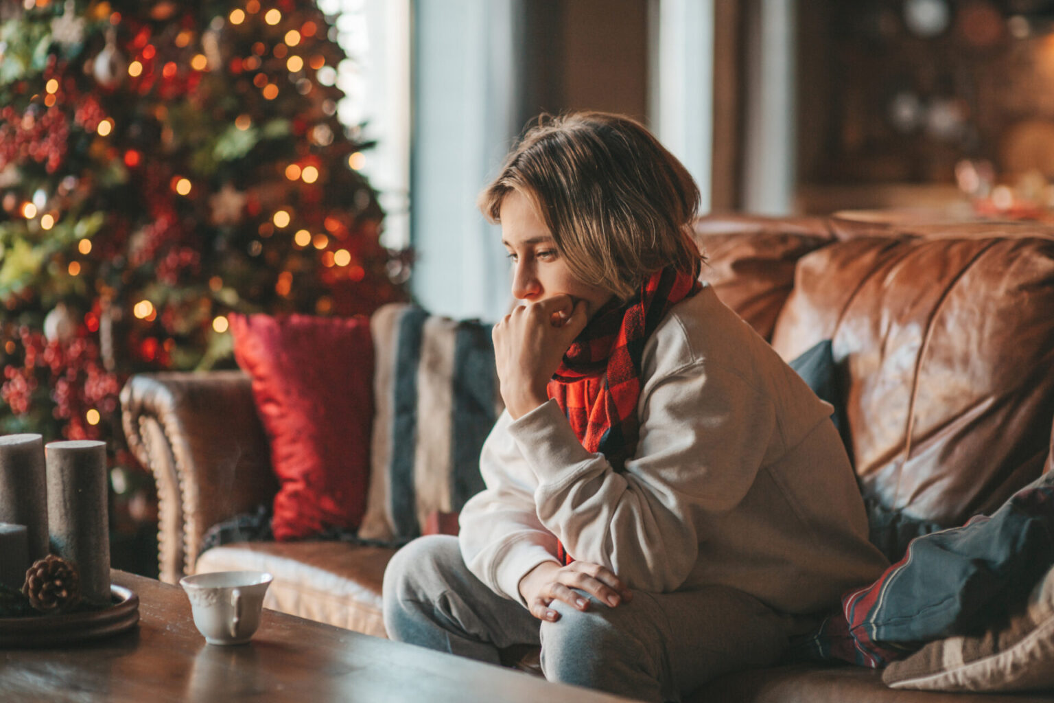 Contemplative person in front of Christmas tree, to illustrate if the holidays are affecting your mental health