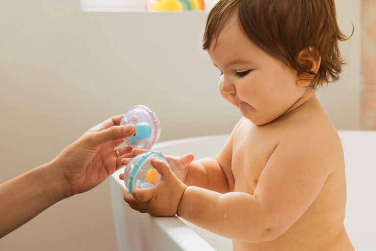 Baby in bathtub playing with toys