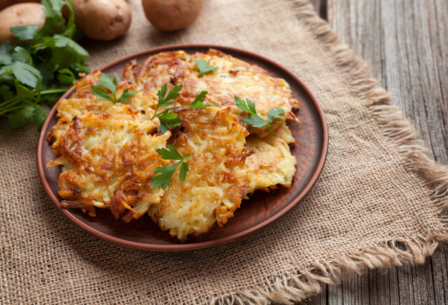 Golden fried potato latkes on a brown plate