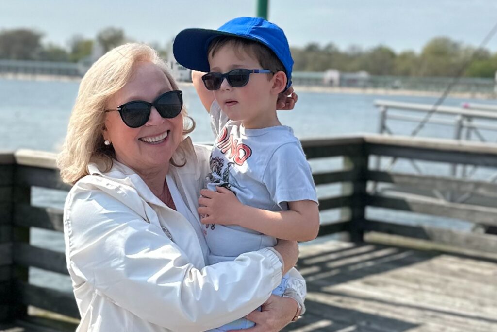 A grandparent holds her grandchild on a pier