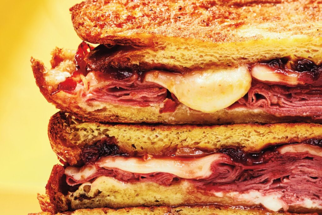 A stack of monte cristo sandwiches filled with pastrami and cheese