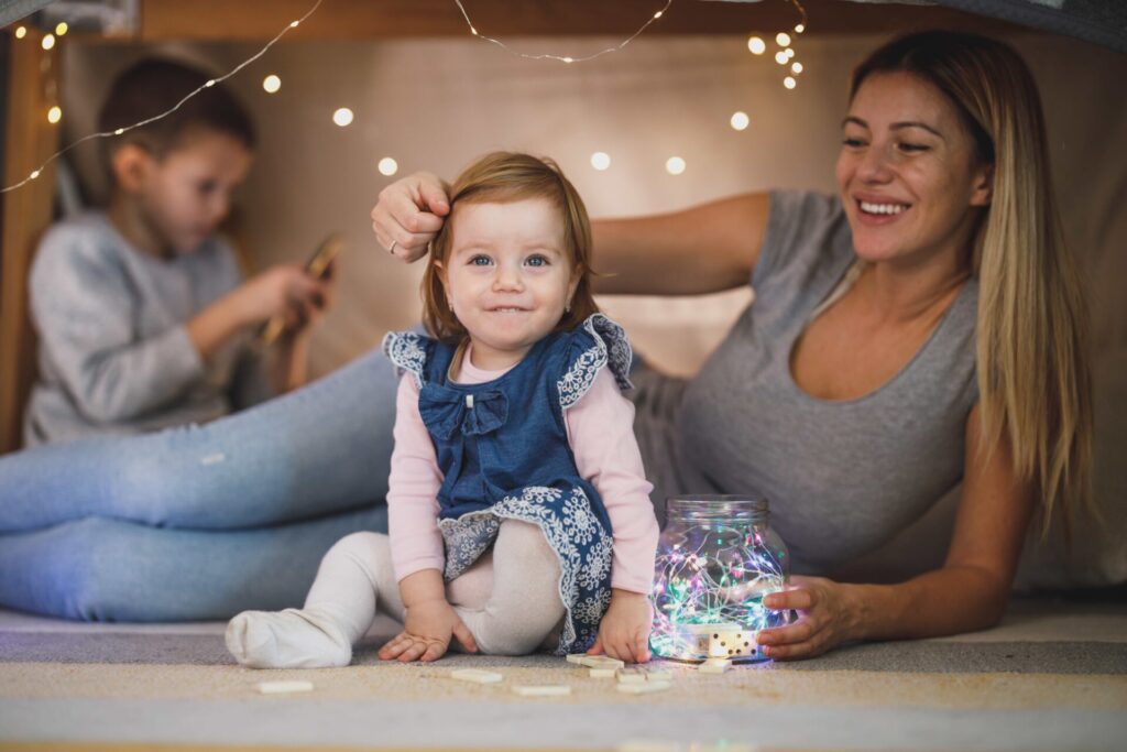 Mother playing with young daughter, son in background, to illustrate parental favouritism