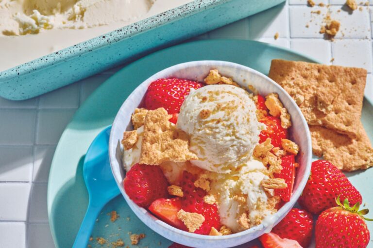 Bowl of cheesecake ice cream with graham crackers and strawberries