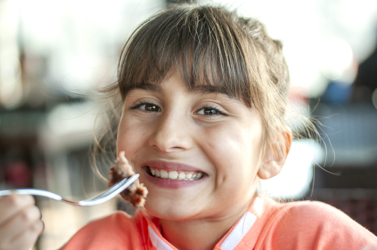 Teen girl eating a meatball.
