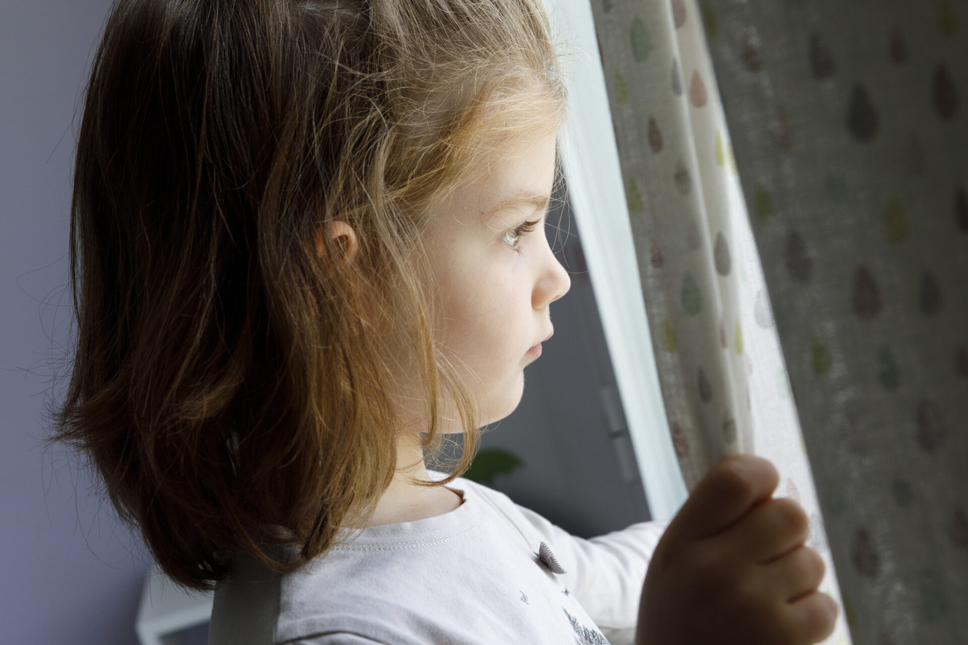 Little girl looking out the winter, to illustrate the tough time of year called the Winter Wall