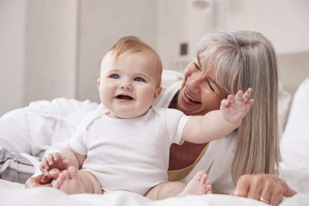 Grandmother looking at grandbaby while sitting on the bed