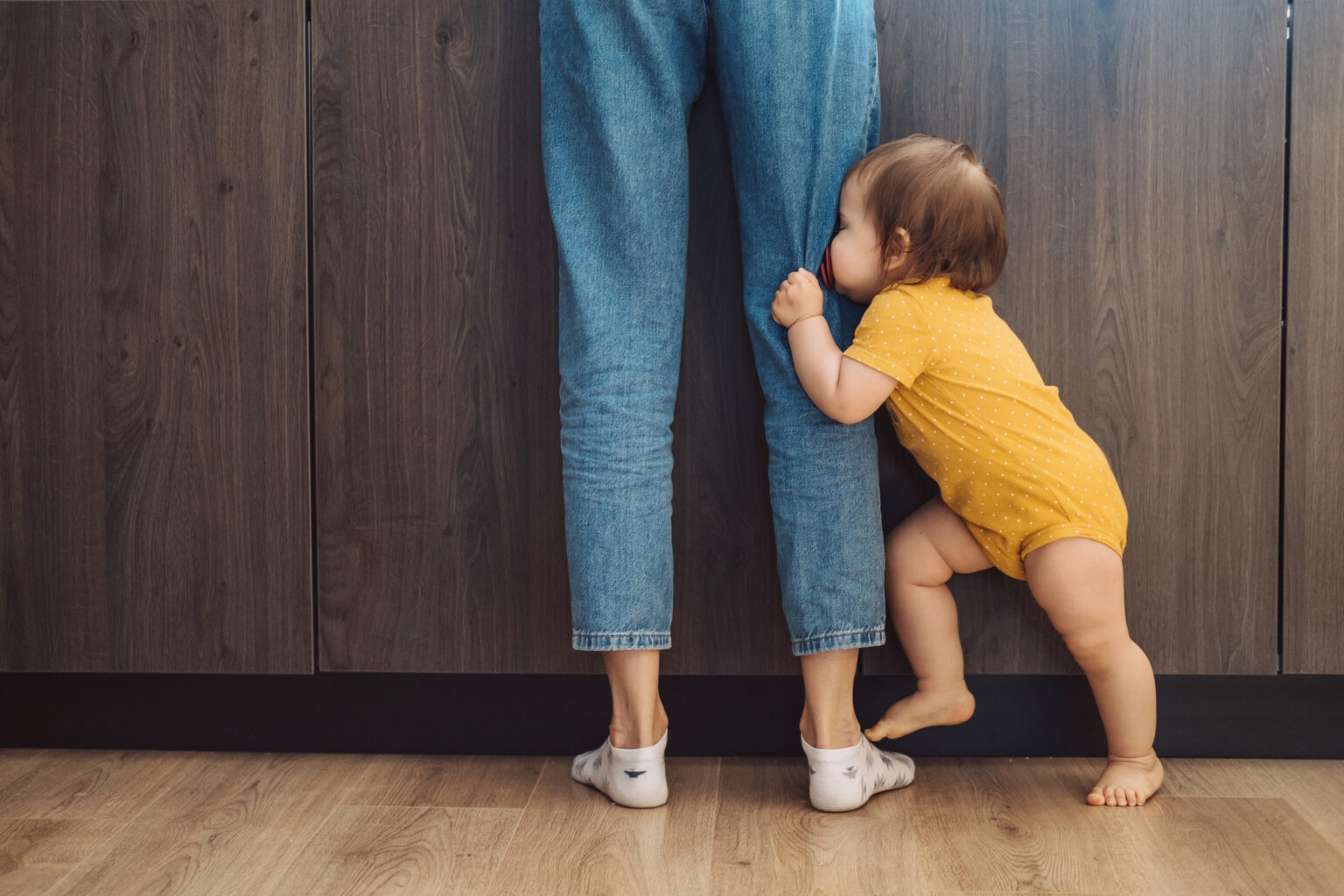 Toddler hanging on parent's leg, to illustrate feeling "touched out"