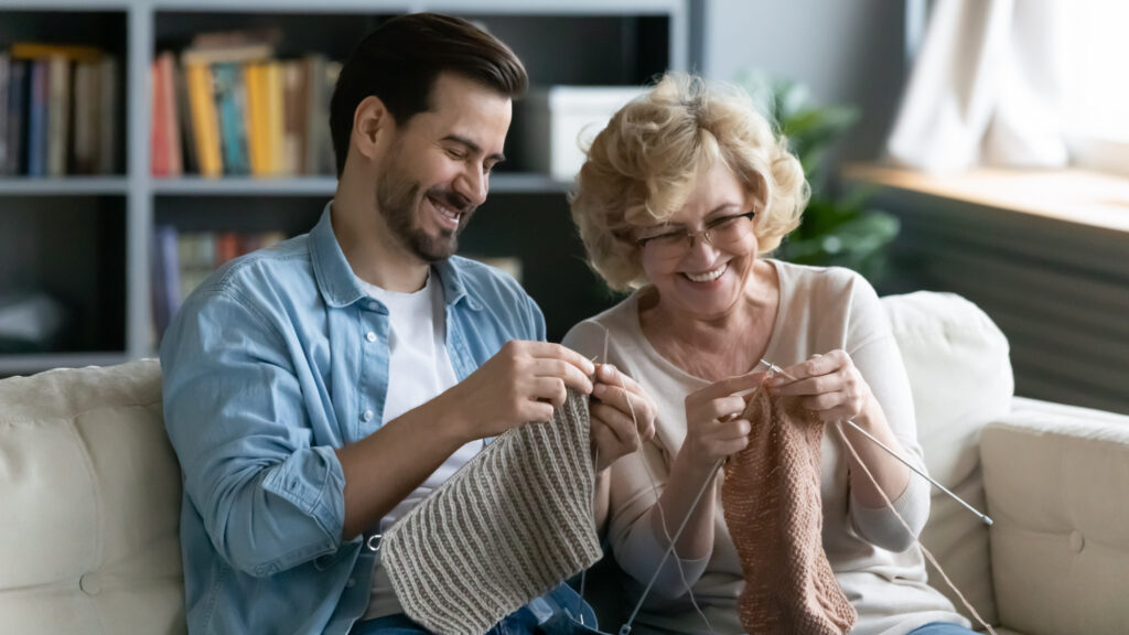Grandparent and Gen Z man knitting to illustrate "grandma hobbies"