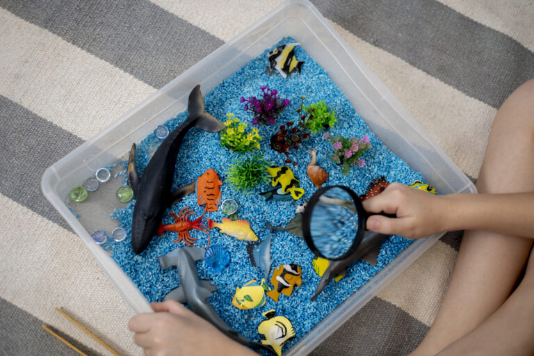 Blue beads with plastic dinosaurs to show basic sensory bins