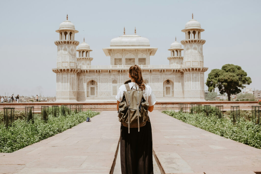a woman stands in front of a castle with a backpack on