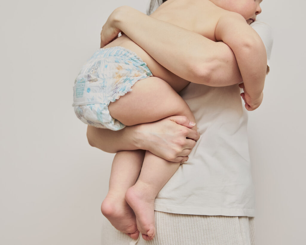 Baby wearing Pampers Swaddlers newborn diaper in mom's arms