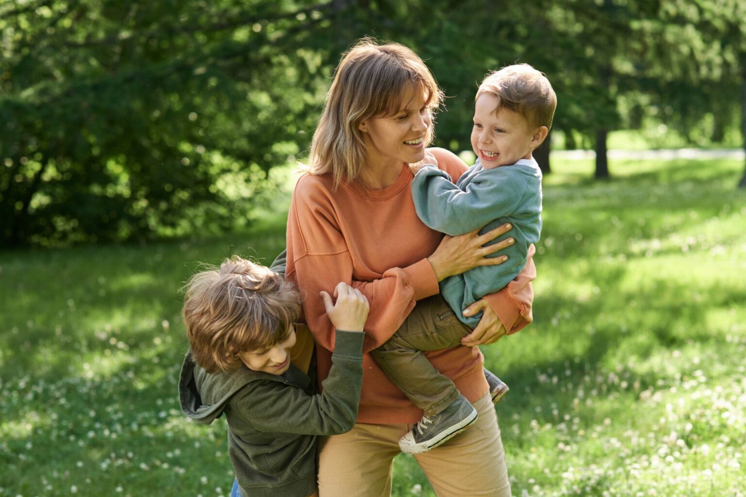A mother and two kids smile in a field