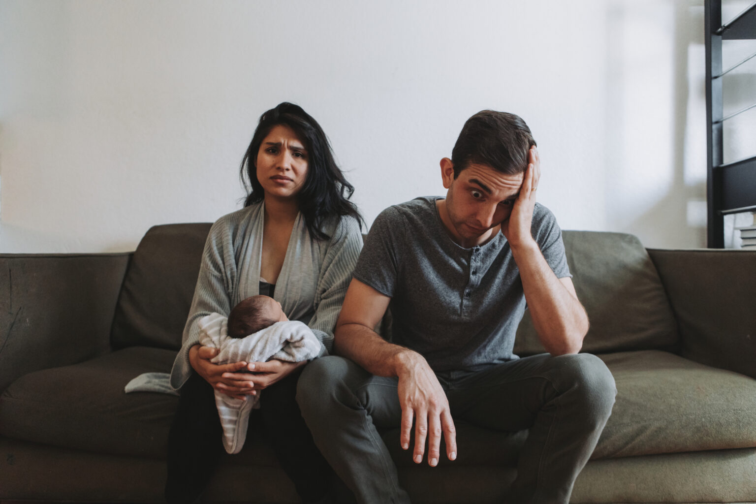 Tired parents holding infant, wondering about soulmate culture and their marriage