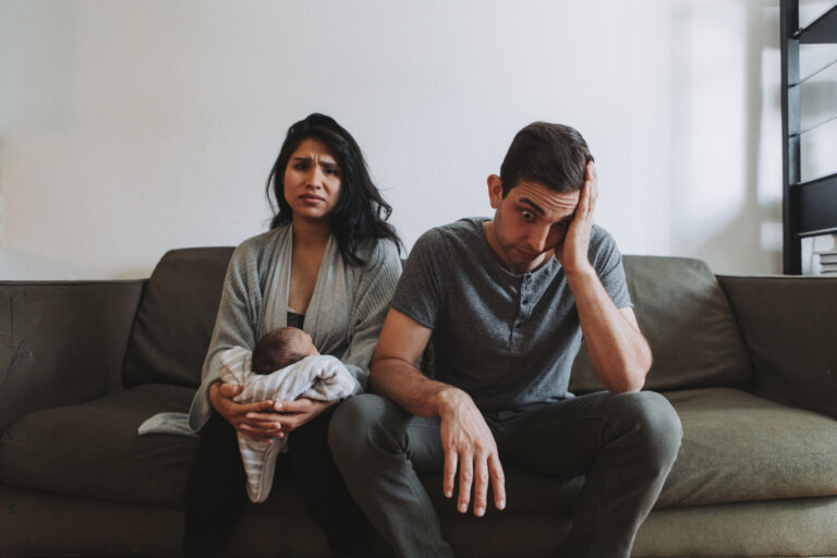 Tired parents holding infant, wondering about soulmate culture and their marriage