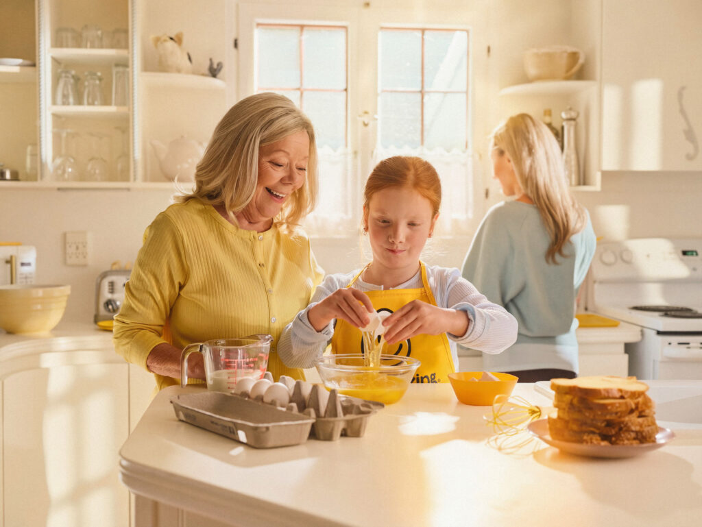 Grandparent cracking eggs with grand daughter