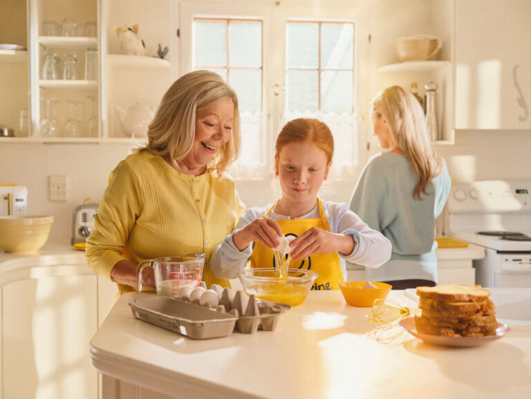 Grandparent cracking eggs with grand daughter
