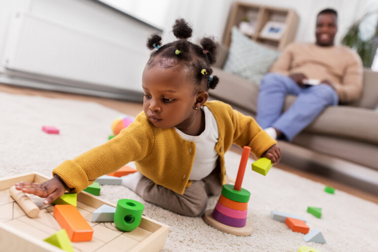 Toddler playing with blocks as parent looks on, to illustrate how to create a "yes space"